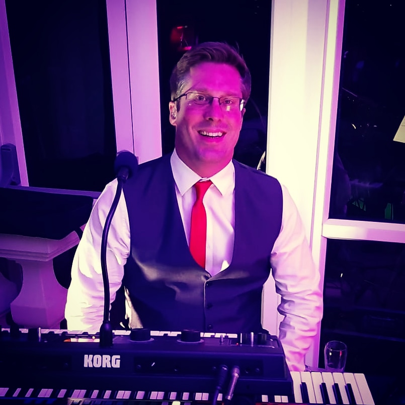 barber using styling spray on young man with black hair, short on sides and long in a quiff on top